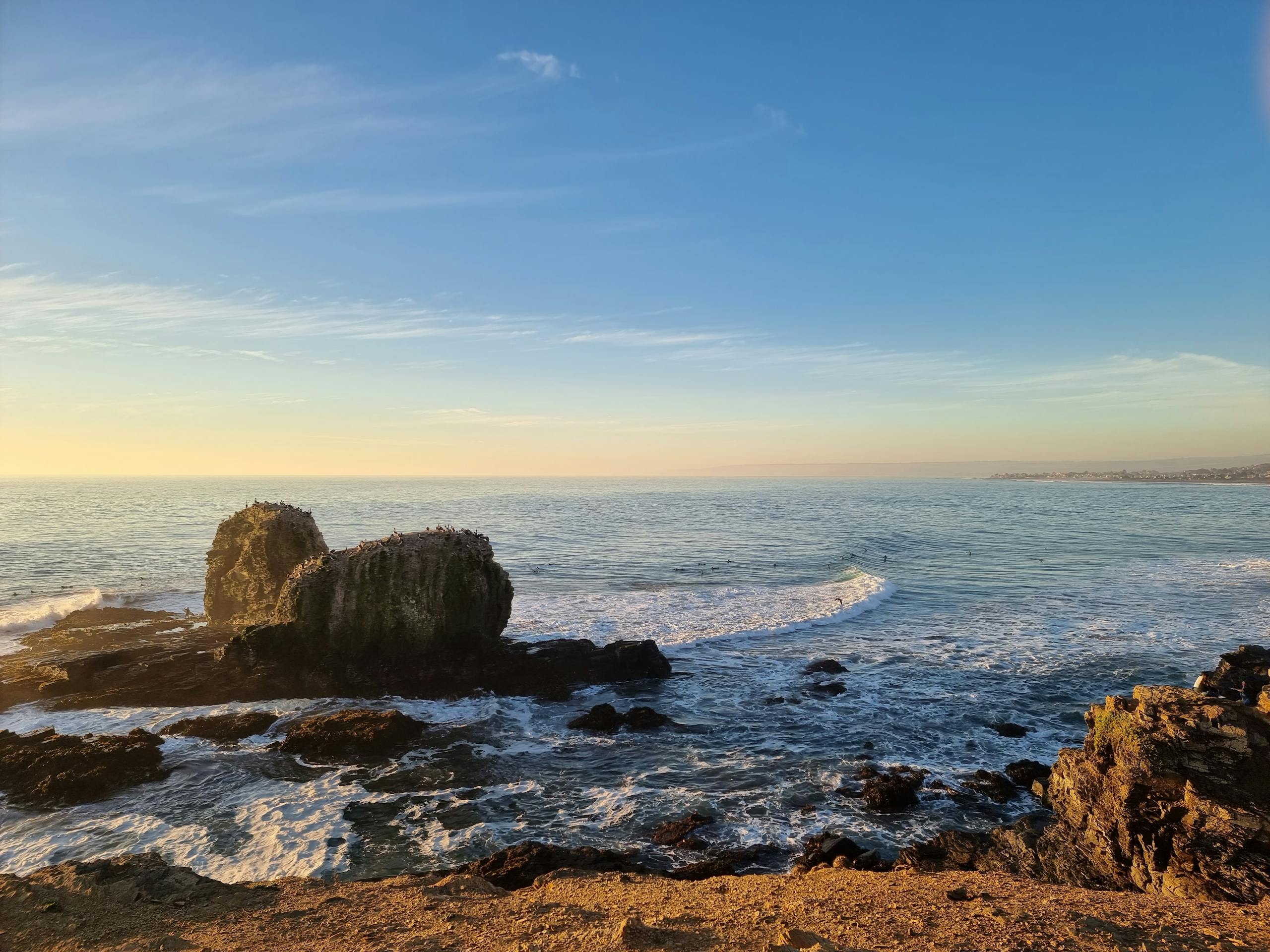 Ocean waves against rocks at Pichilemu, Chile, during a serene sunset.