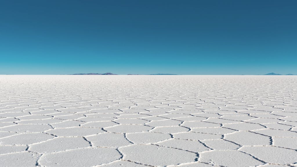 Vast salar with geometric patterns under a clear blue sky in Bolivia's Uyuni.