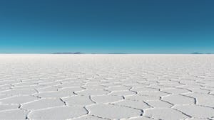 Vast salar with geometric patterns under a clear blue sky in Bolivia's Uyuni.
